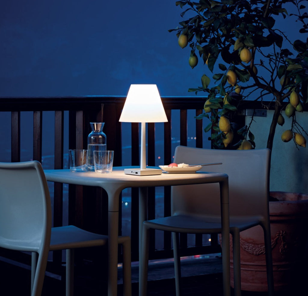Een sfeervol verlicht terras in de avond met stijlvolle, draadloze oplaadbare lampen voor buiten op een tafel